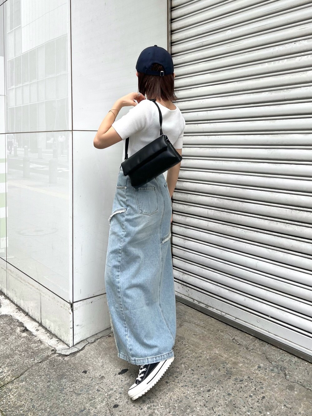 ホワイト系のニット/セーター、ブルー系のデニムスカート、ブラック系のハンドバッグを着用したレディースの夏コーディネートの2枚目の写真