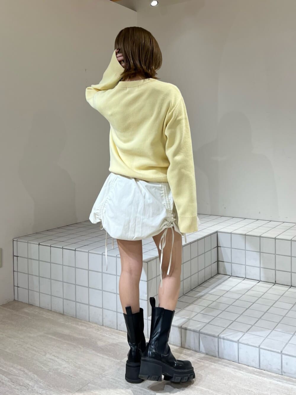 イエロー系のカーディガン/ボレロ、ホワイト系のスカートを着用したレディースの冬コーディネートの3枚目の写真