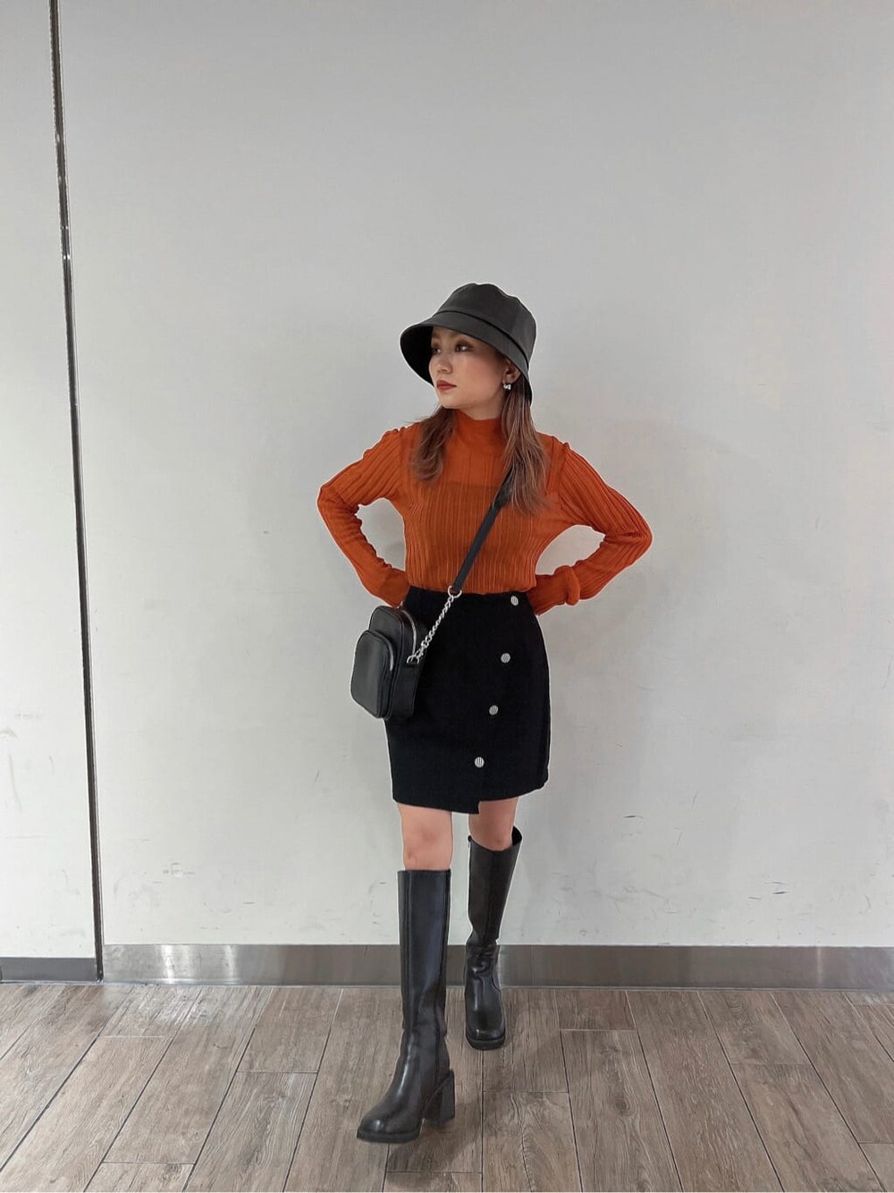 ブラック系のブーツ、オレンジ系のニット/セーター、ブラック系のスカートを着用したレディースの秋コーディネートの4枚目の写真