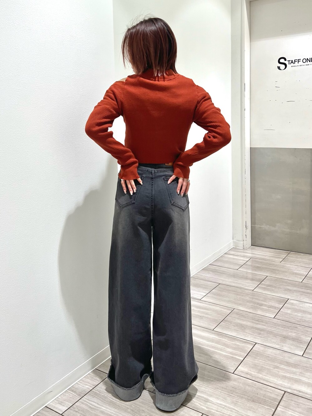 オレンジ系のニット/セーター、グレー系のデニムパンツを着用したレディースの冬コーディネートの3枚目の写真