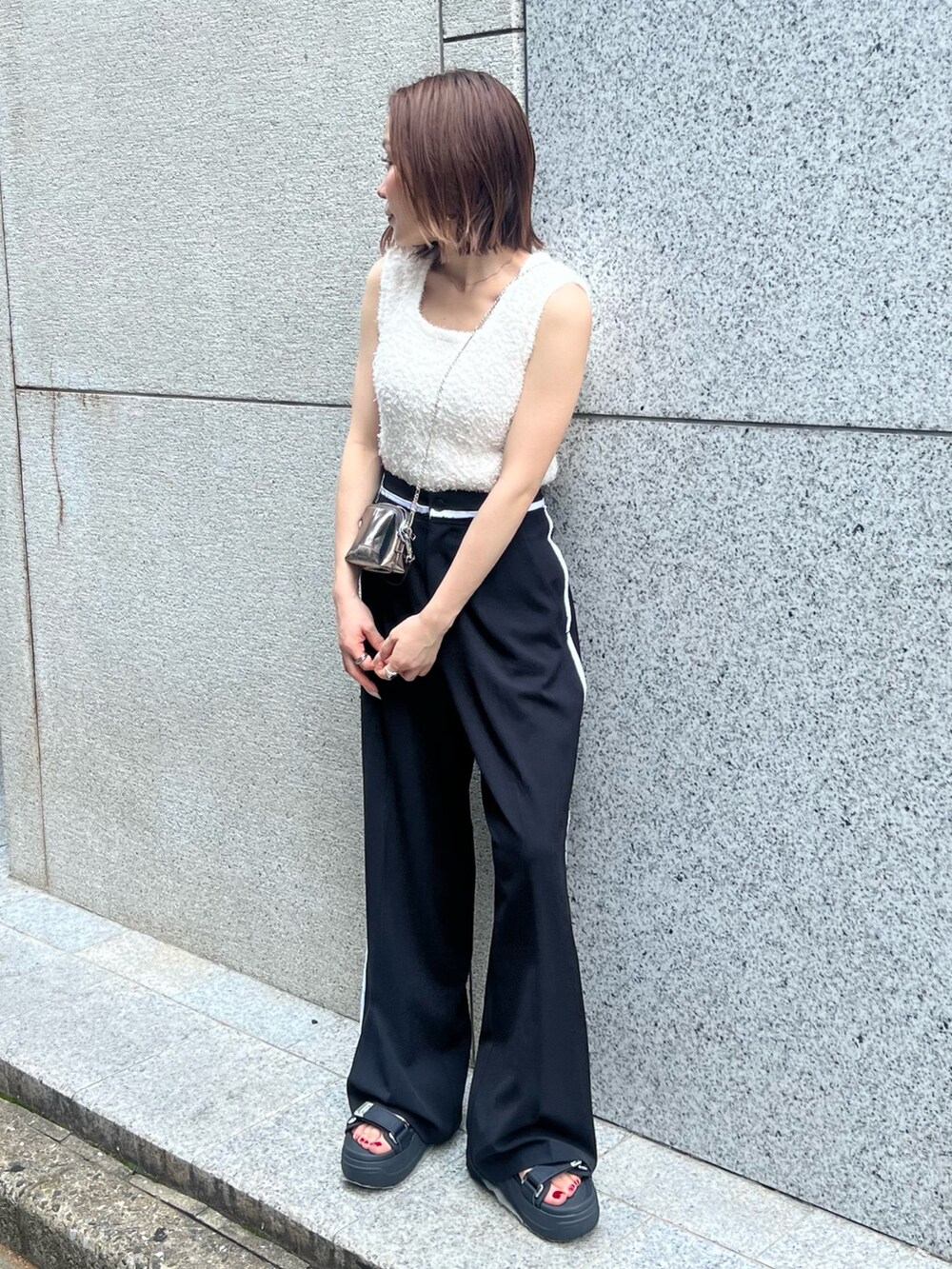 ホワイト系のニット/セーター、ブラック系のその他パンツ、ゴールド系のショルダーバッグを着用したレディースの夏コーディネートの4枚目の写真
