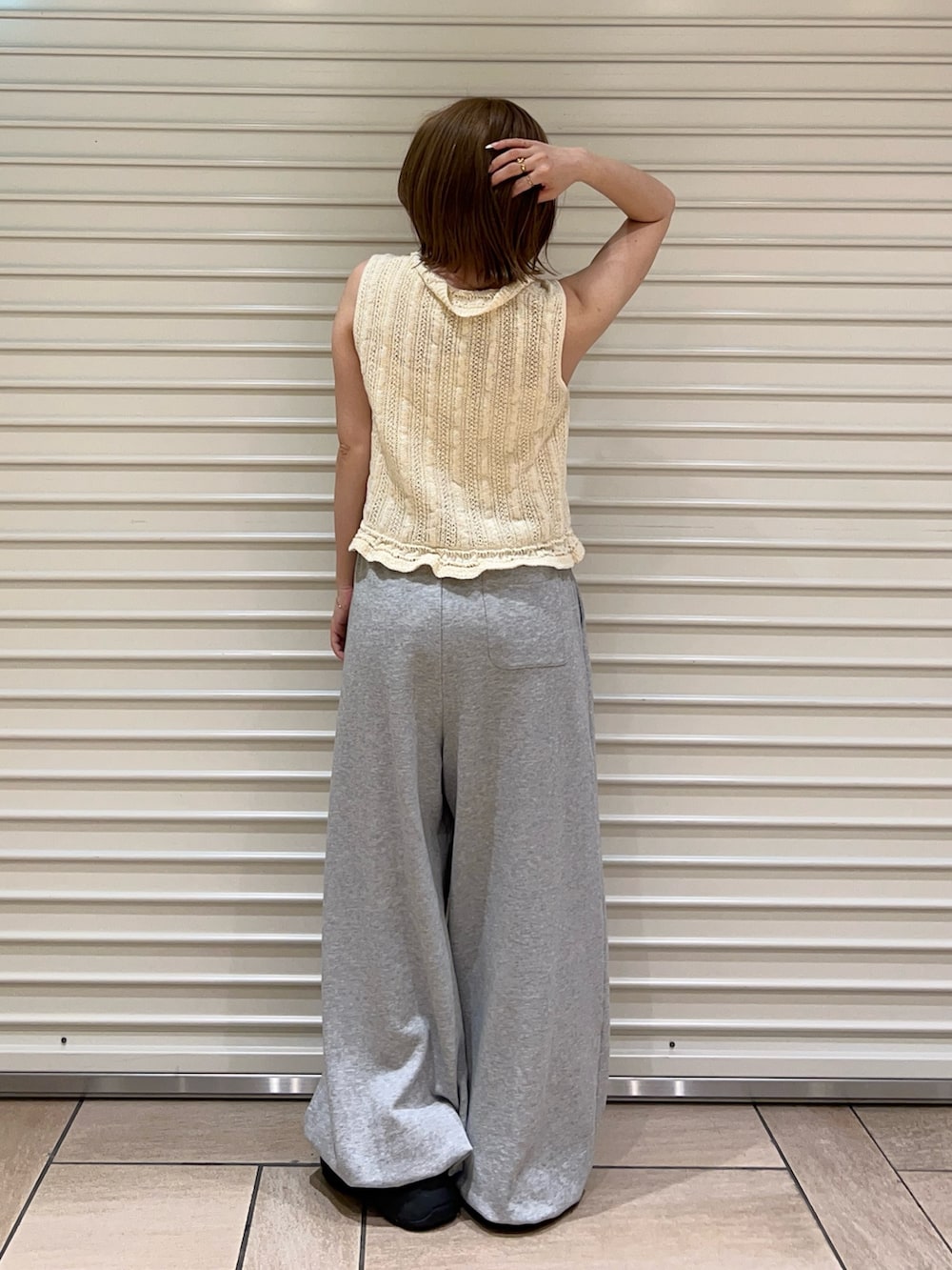 ホワイト系のニット/セーター、グレー系のスウェットパンツを着用したレディースの夏コーディネートの3枚目の写真