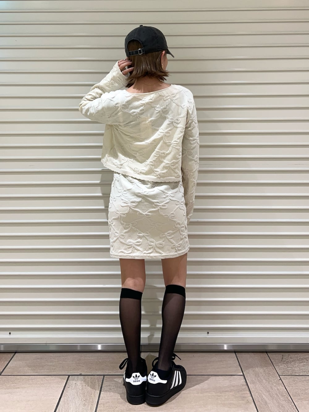 ホワイト系のワンピース、ホワイト系のカーディガン/ボレロ、ブラック系のキャップを着用したレディースの冬コーディネートの3枚目の写真