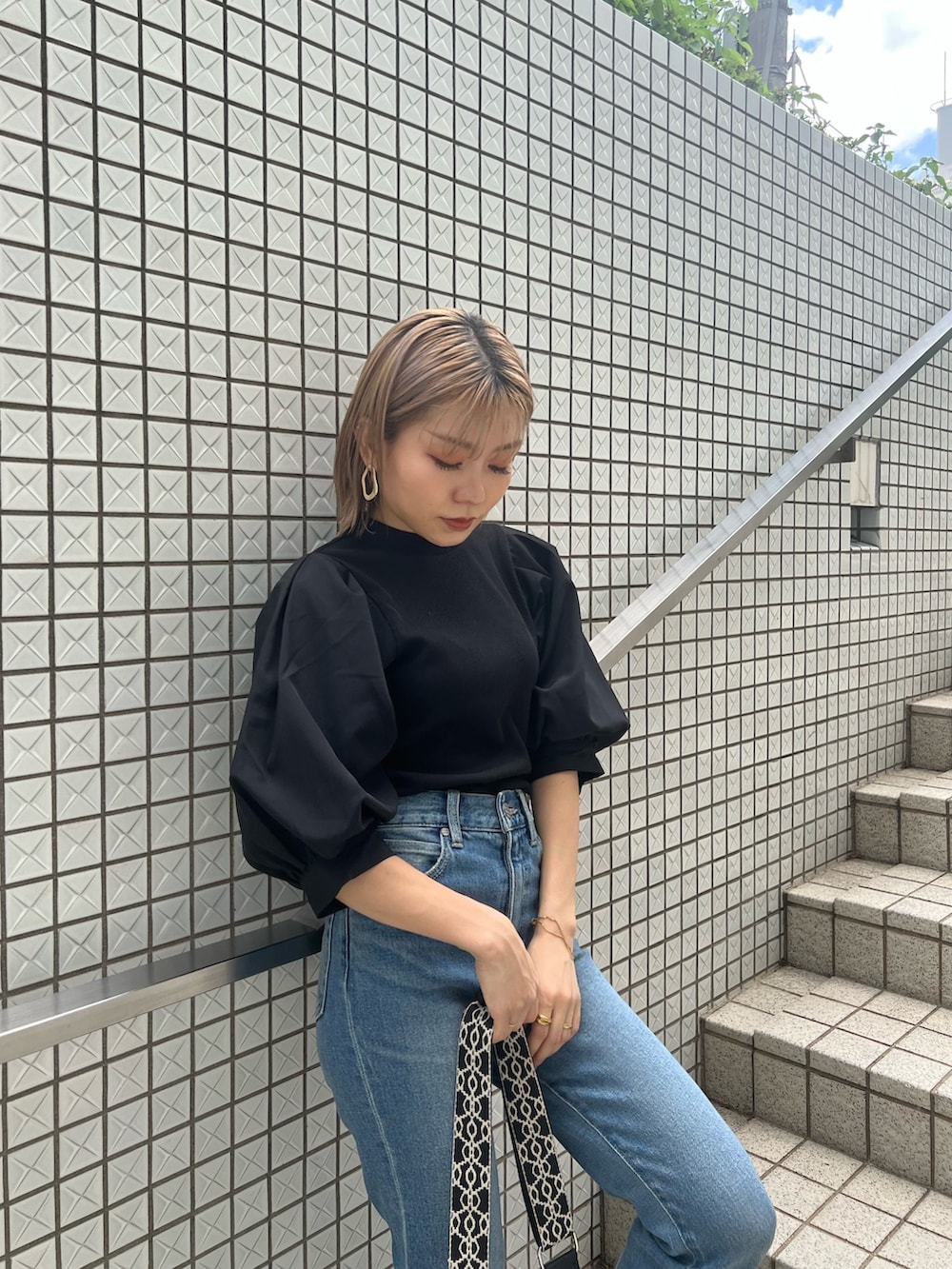 ブルー系のデニムパンツ、ブラック系のTシャツ/カットソー、ブラック系のショルダーバッグを着用したレディースの夏コーディネートの4枚目の写真