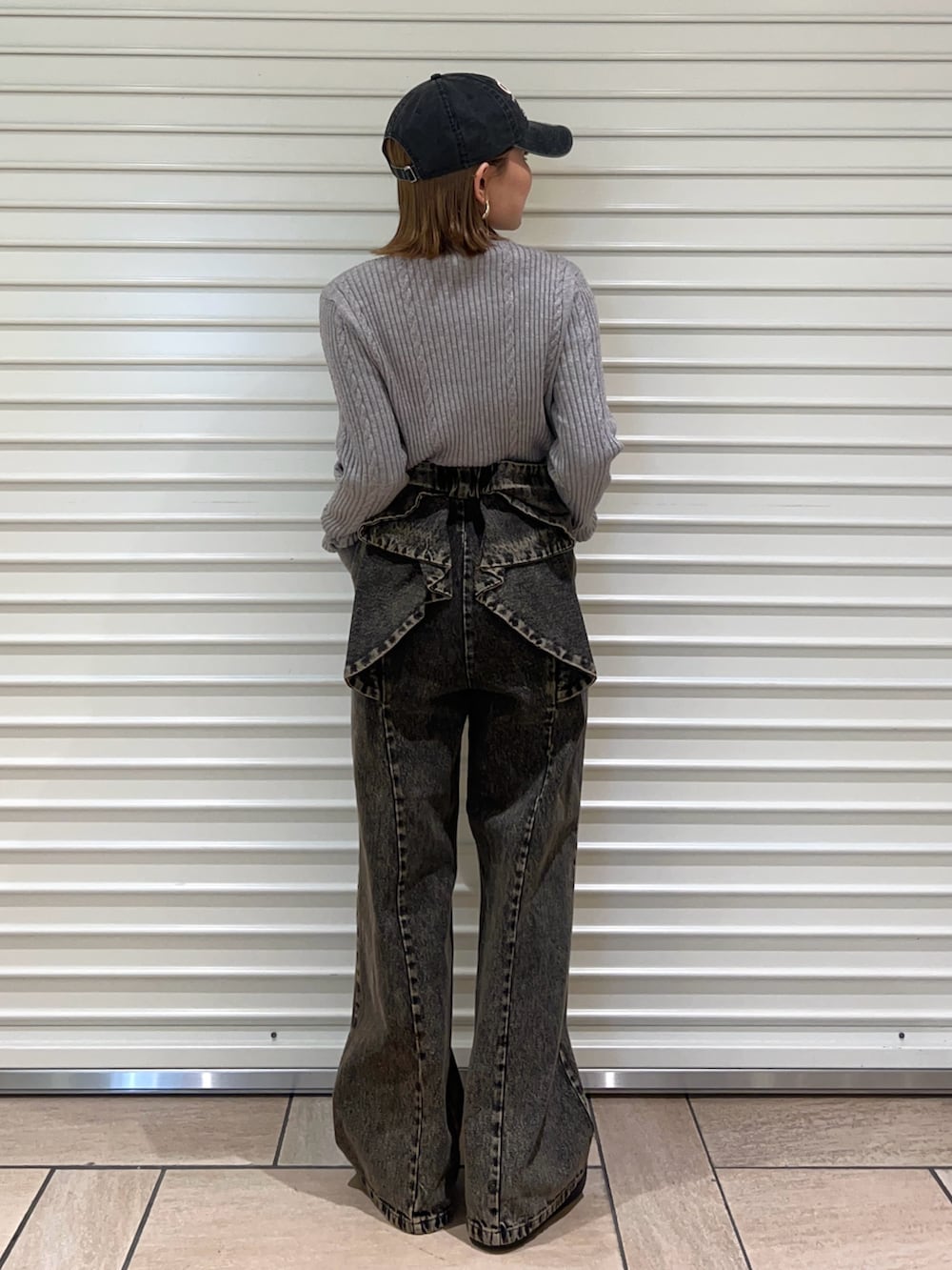 グレー系のニット/セーター、ブラック系のデニムパンツ、ブラック系のキャップを着用したレディースの冬コーディネートの3枚目の写真