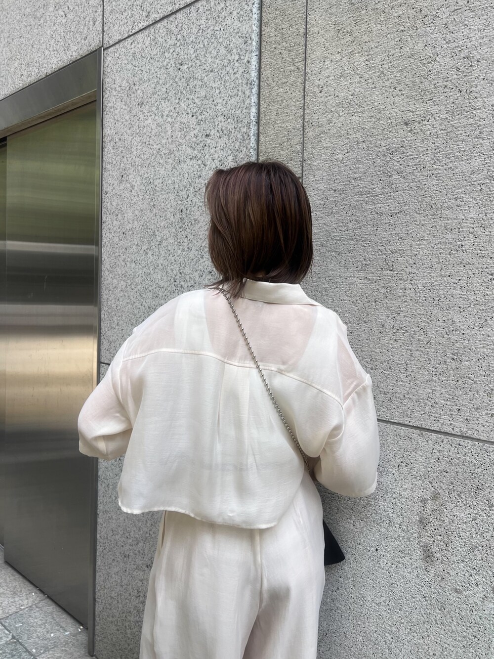 ホワイト系のシャツ/ブラウス、ホワイト系のニット/セーター、ブラック系のショルダーバッグを着用したレディースの夏コーディネートの6枚目の写真