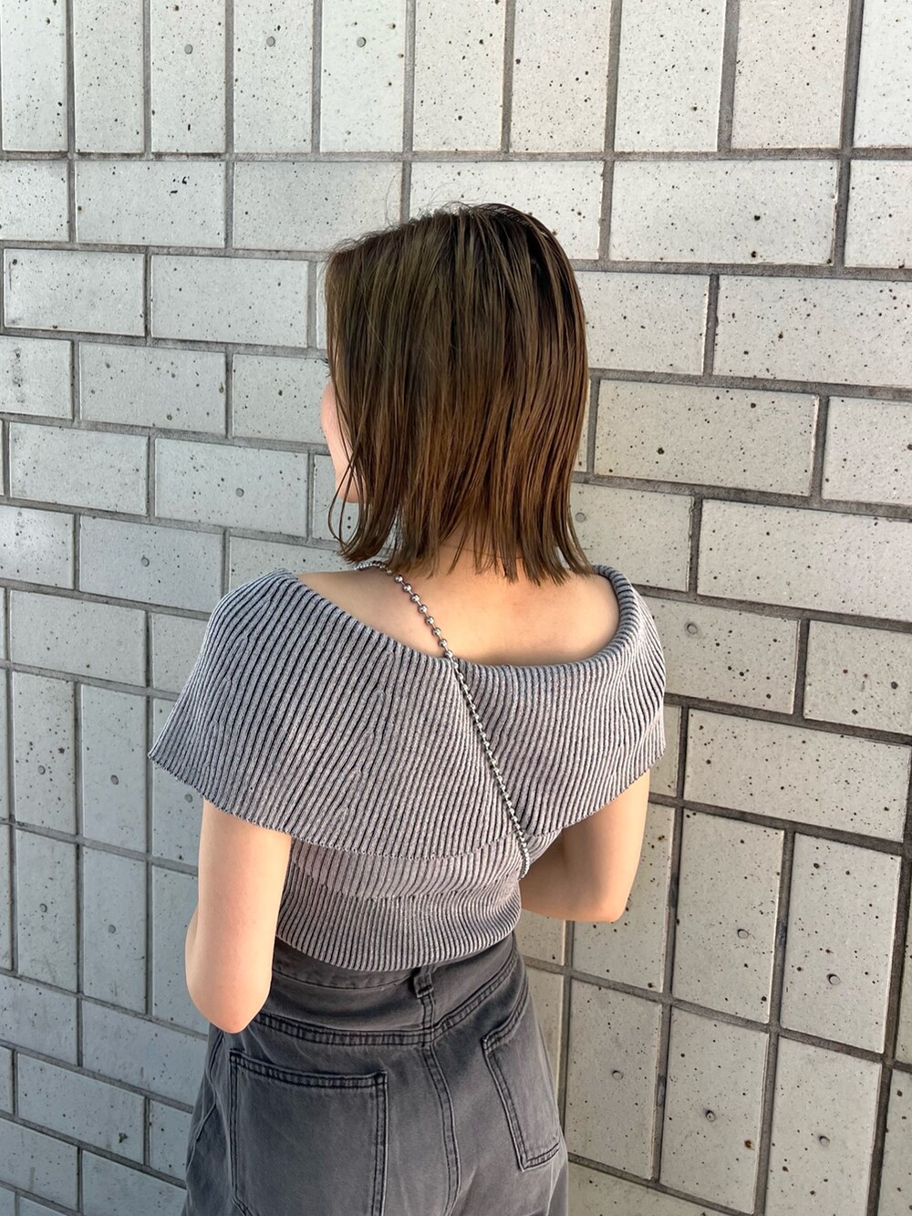 グレー系のニット/セーター、ブラック系のデニムパンツ、ブラック系のサンダルを着用したレディースの春コーディネートの6枚目の写真