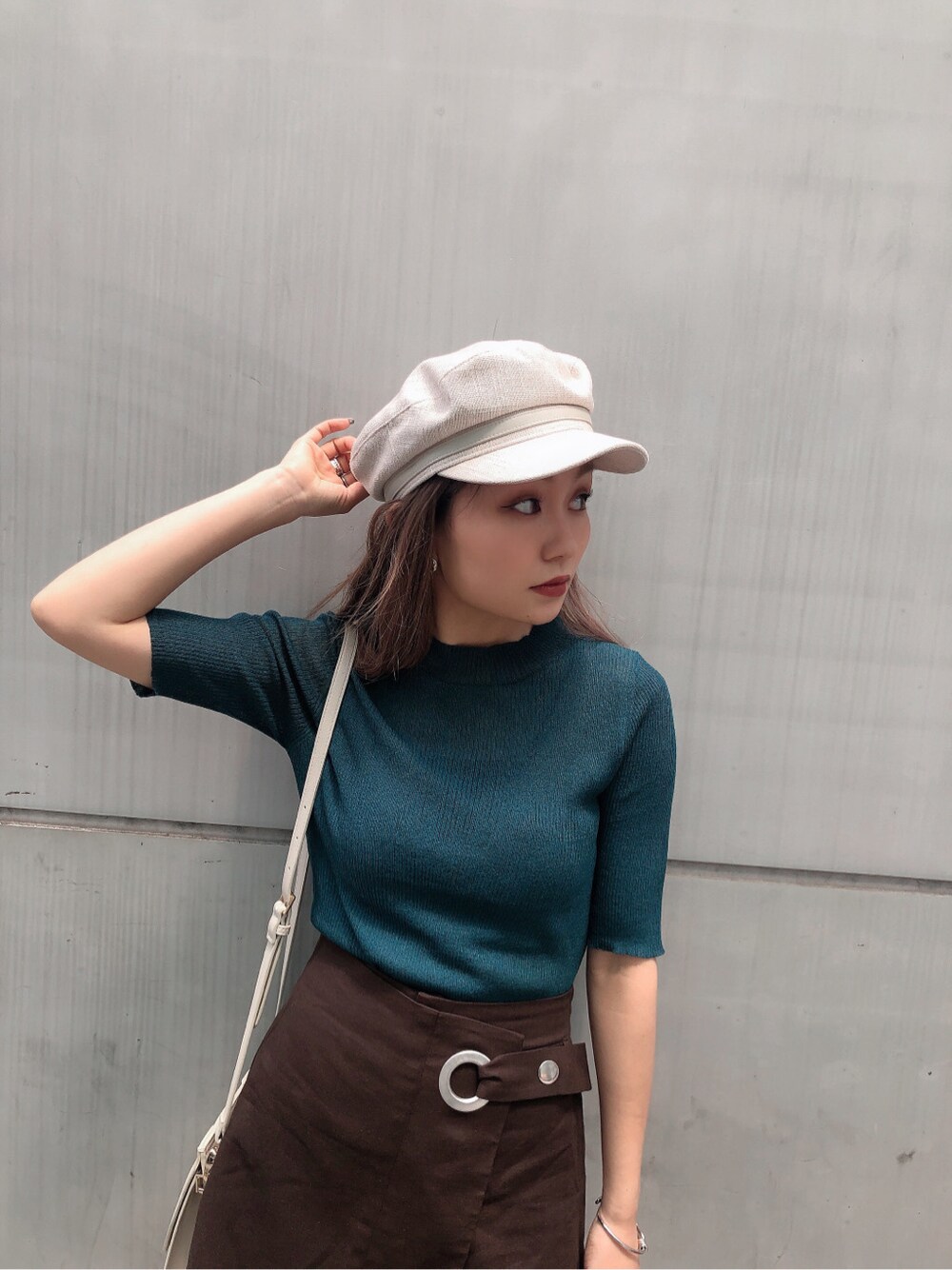 ホワイト系のハンドバッグ、ホワイト系のサンダル、グリーン系のニット/セーターを着用したレディースの夏コーディネートの3枚目の写真