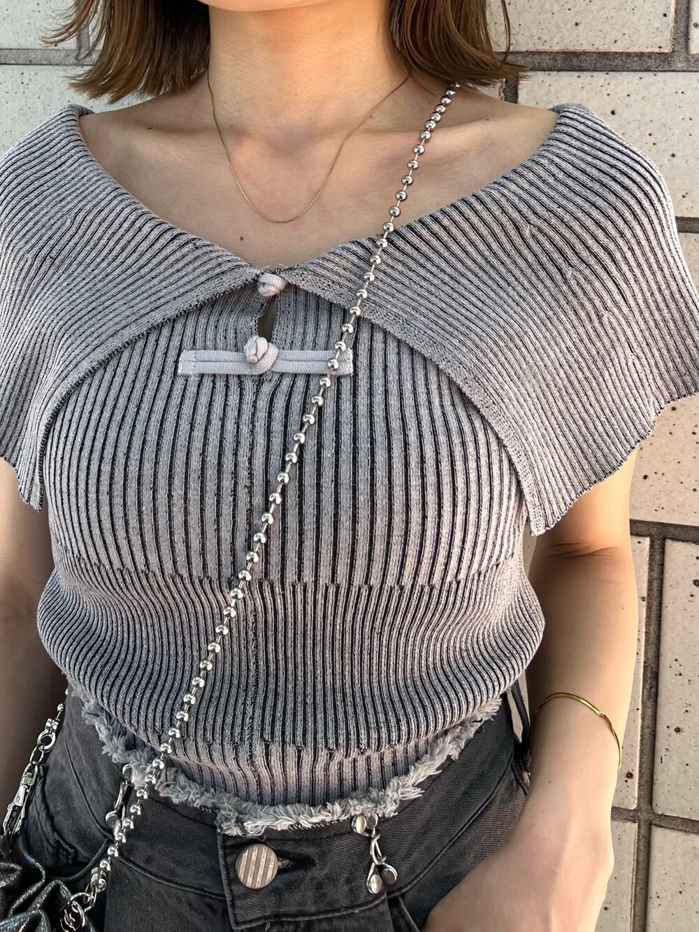 グレー系のニット/セーター、ブラック系のデニムパンツ、ブラック系のサンダルを着用したレディースの春コーディネートの8枚目の写真