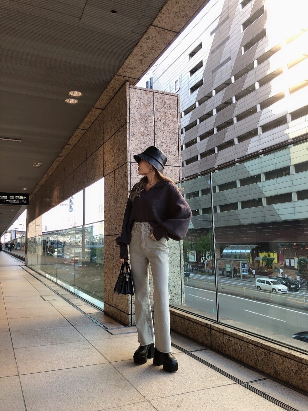 グレー系のデニムパンツ、グレー系のニット/セーター、ブラック系のハンドバッグを着用したレディースの秋コーディネートの2枚目の写真