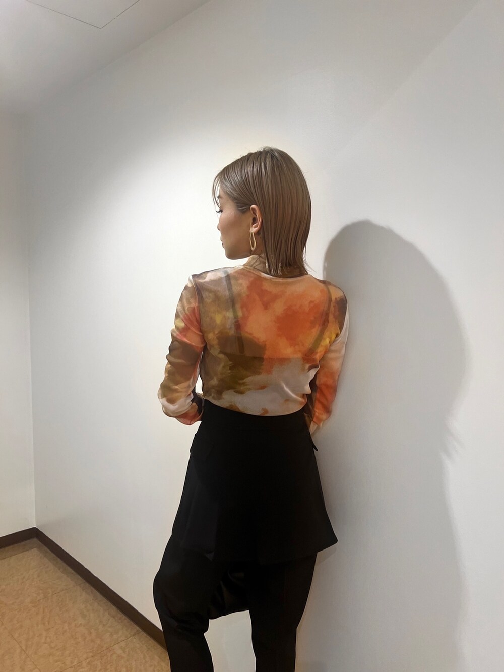 オレンジ系のTシャツ/カットソー、ブラック系のブーツ、ブラック系のスラックスを着用したレディースの夏コーディネートの5枚目の写真