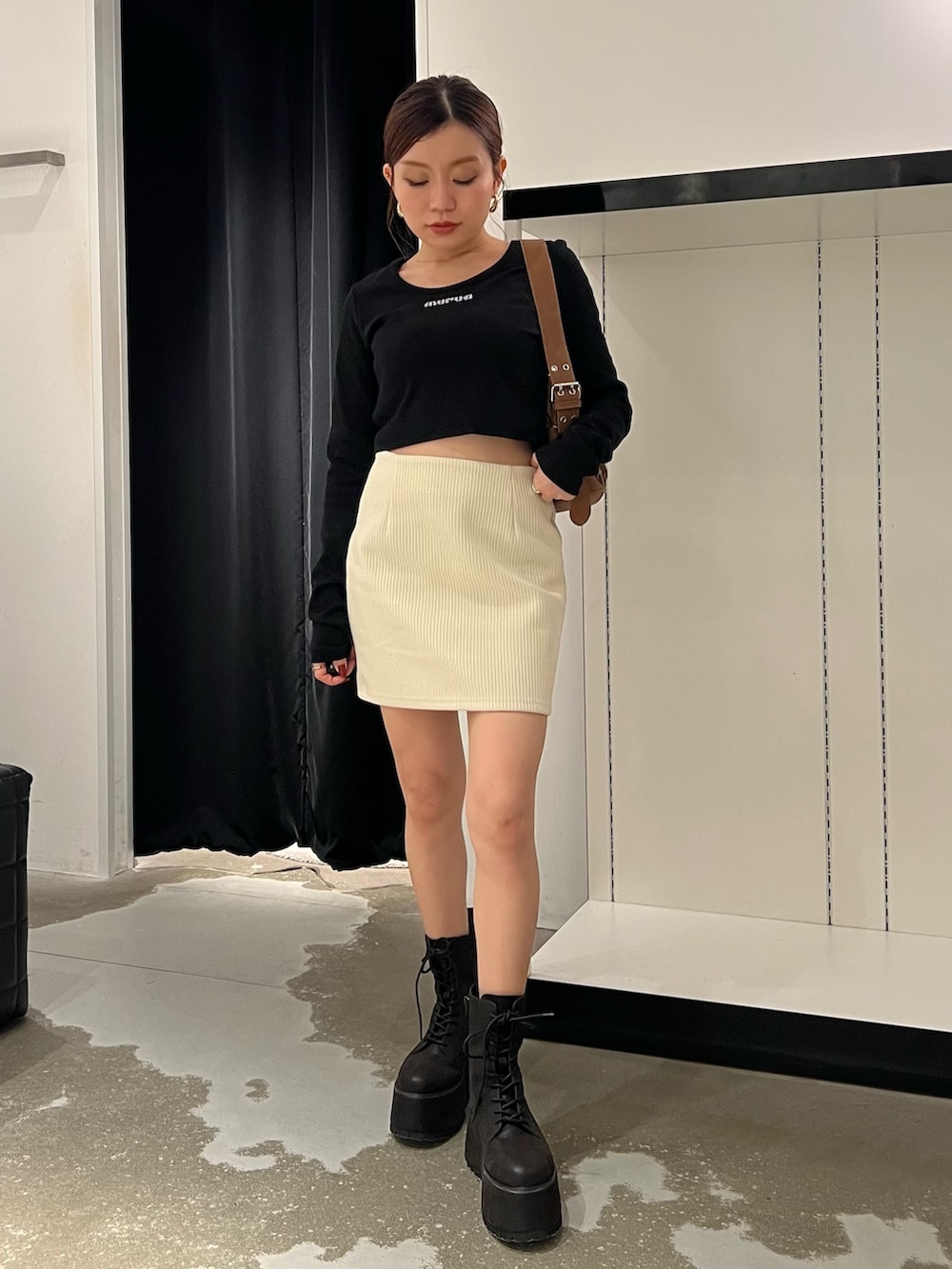 ホワイト系のスカート、ブラック系のTシャツ/カットソー、ブラック系のブーツを着用したレディースの秋コーディネートの4枚目の写真