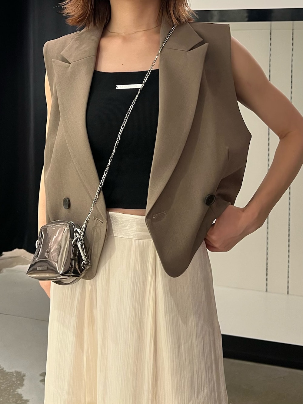 ブラック系のサンダル、ホワイト系のスカート、ゴールド系のショルダーバッグを着用したレディースの夏コーディネートの7枚目の写真