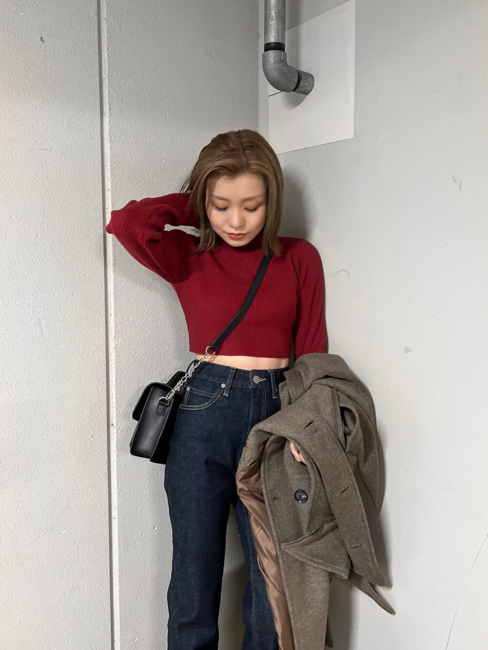 ブルー系のデニムパンツ、ブラウン系のチェスターコート、レッド系のニット/セーターを着用したレディースの秋コーディネートの6枚目の写真