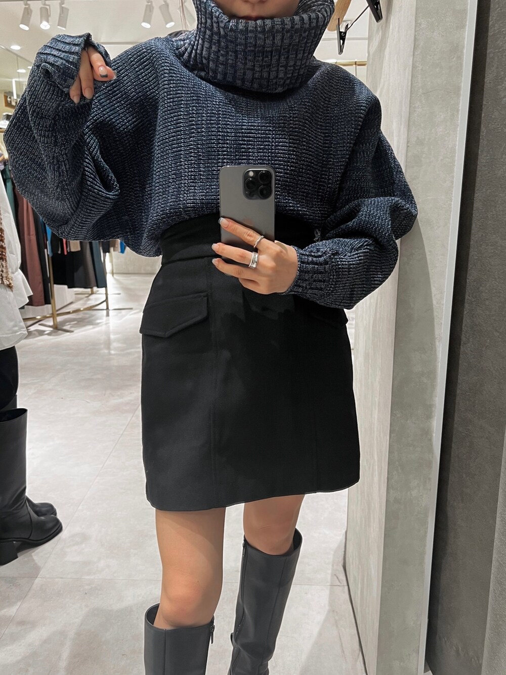 ブラック系のスカート、ブルー系のニット/セーター、ブラック系のブーツを着用したレディースの秋コーディネートの7枚目の写真