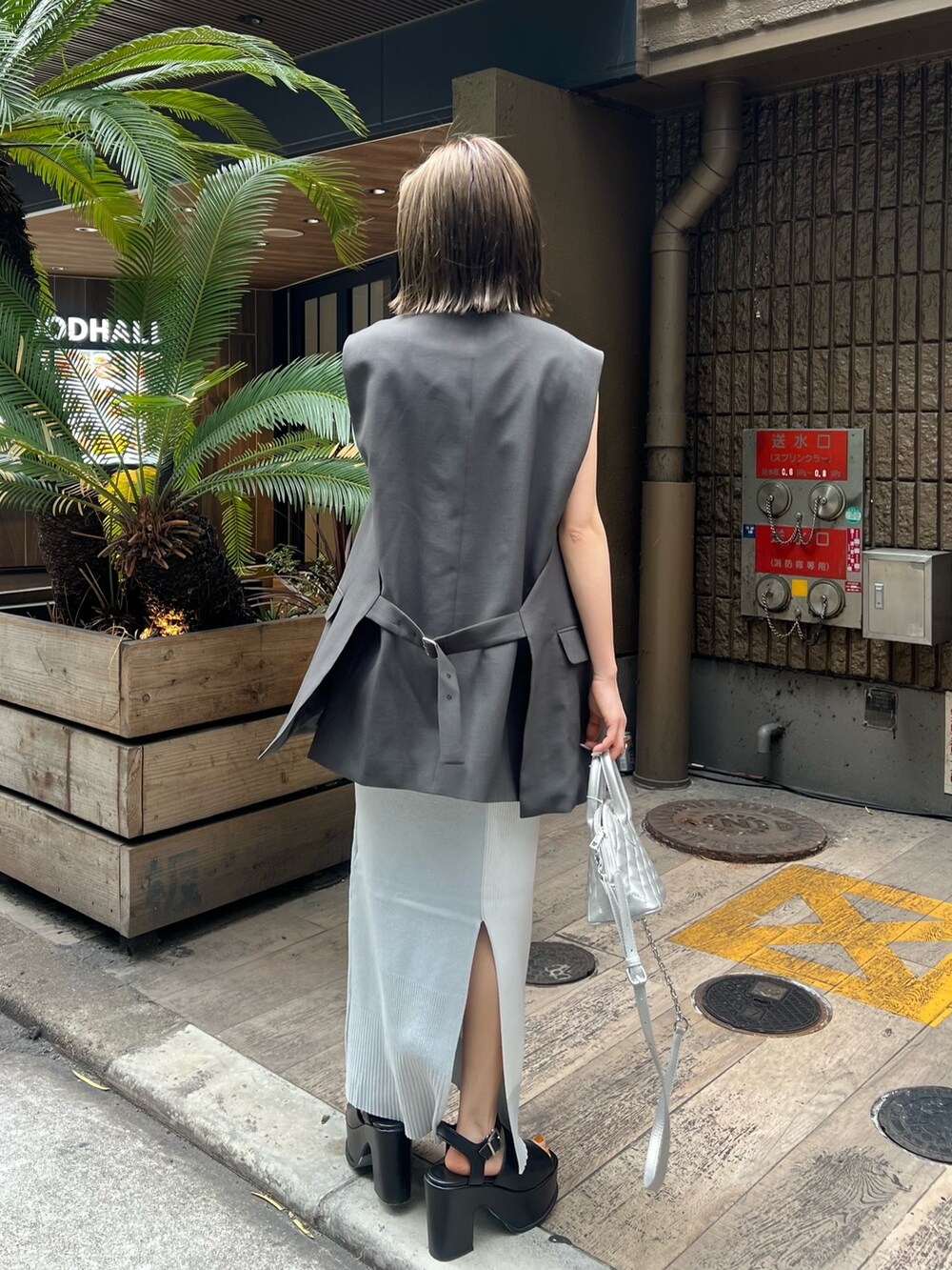 ホワイト系のワンピース、グレー系のベスト、ブラック系のサンダルを着用したレディースの春コーディネートの2枚目の写真