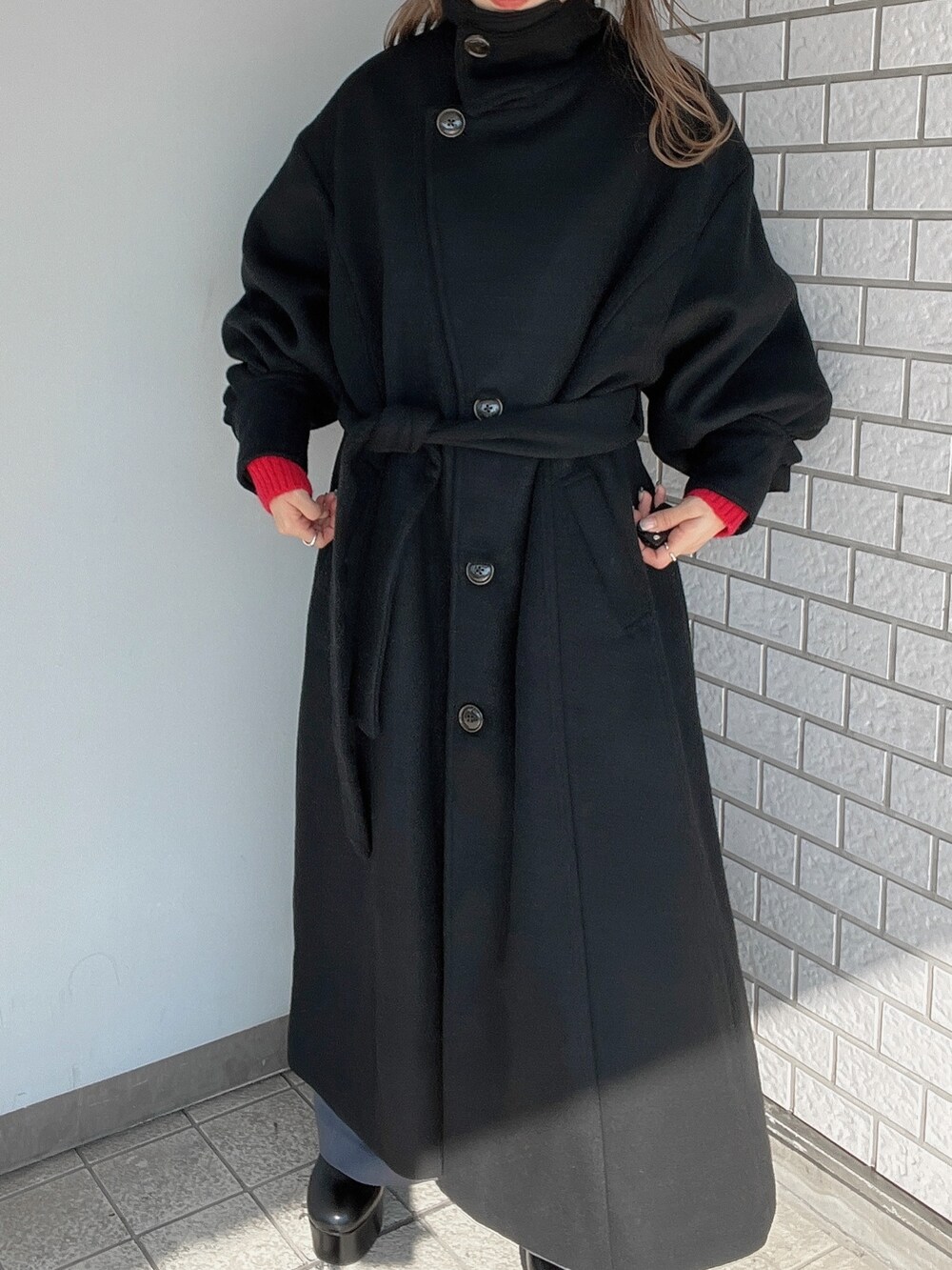 レッド系のニット/セーター、ブラック系のダウンジャケット/コート、ブラック系のブーツを着用したレディースの秋コーディネートの3枚目の写真