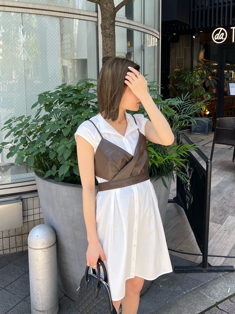 ブラウン系のワンピース、ブラック系のハンドバッグ、ブラック系のブーツを着用したレディースの春コーディネートの4枚目の写真