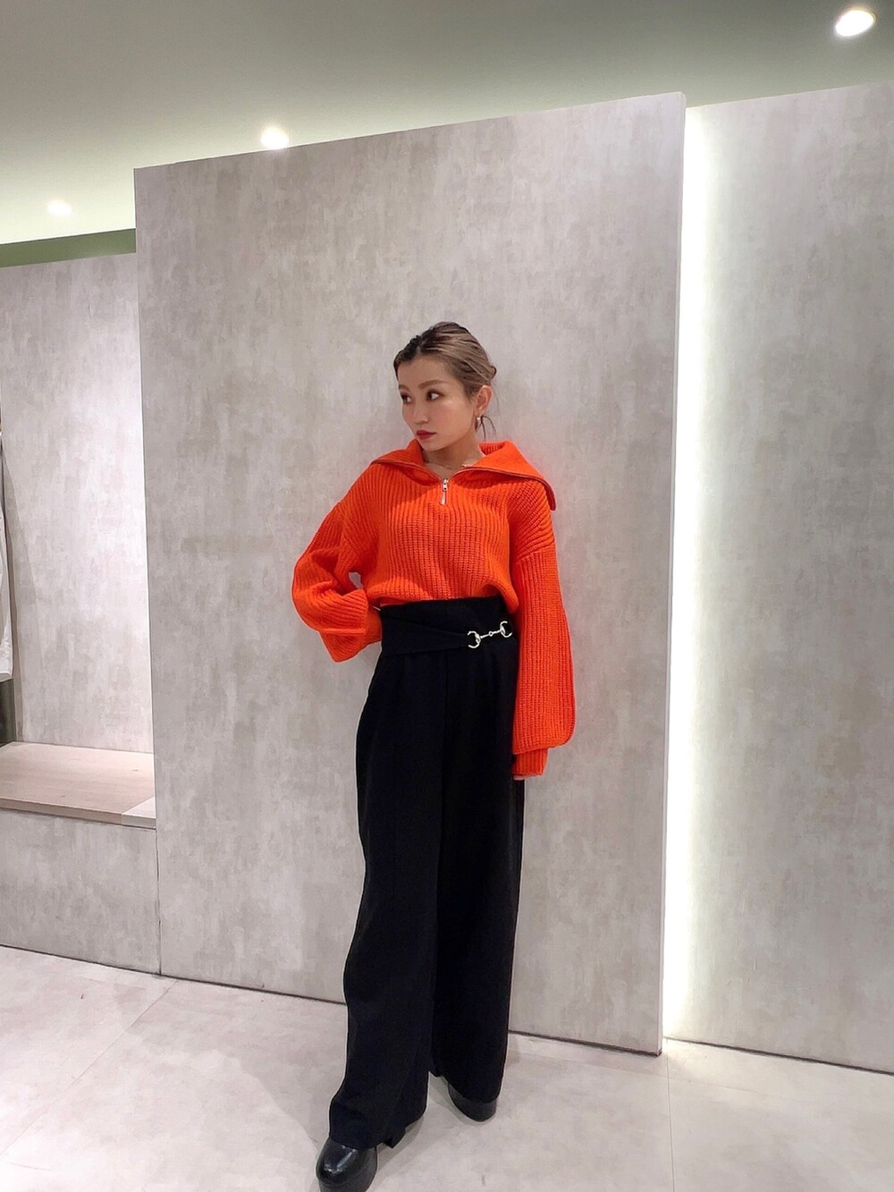 ブラック系のスラックス、オレンジ系のニット/セーター、ブラック系のムートンコートを着用したレディースの冬コーディネートの7枚目の写真