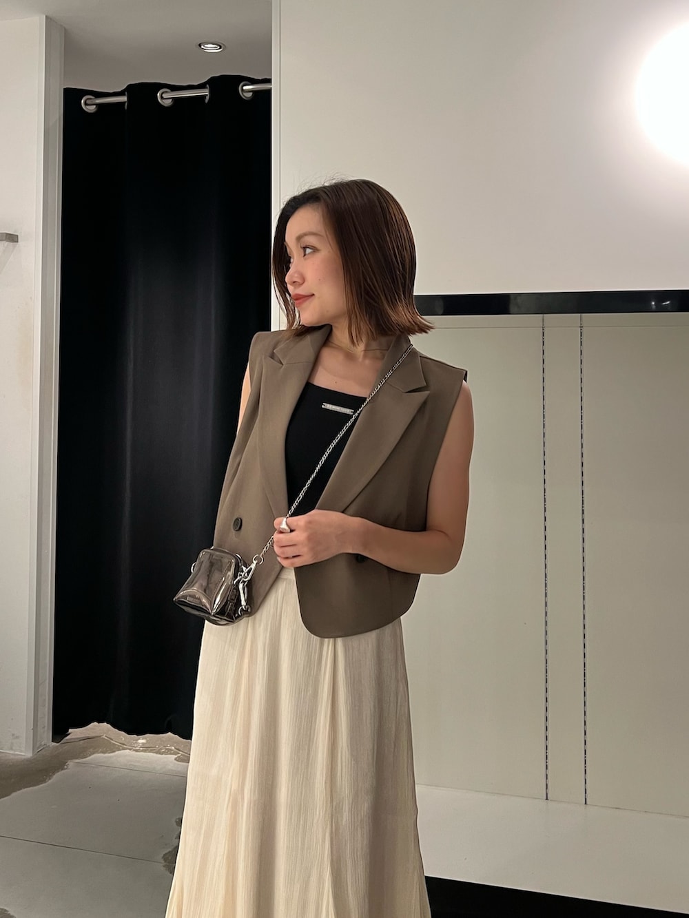 ブラック系のサンダル、ホワイト系のスカート、ゴールド系のショルダーバッグを着用したレディースの夏コーディネートの4枚目の写真