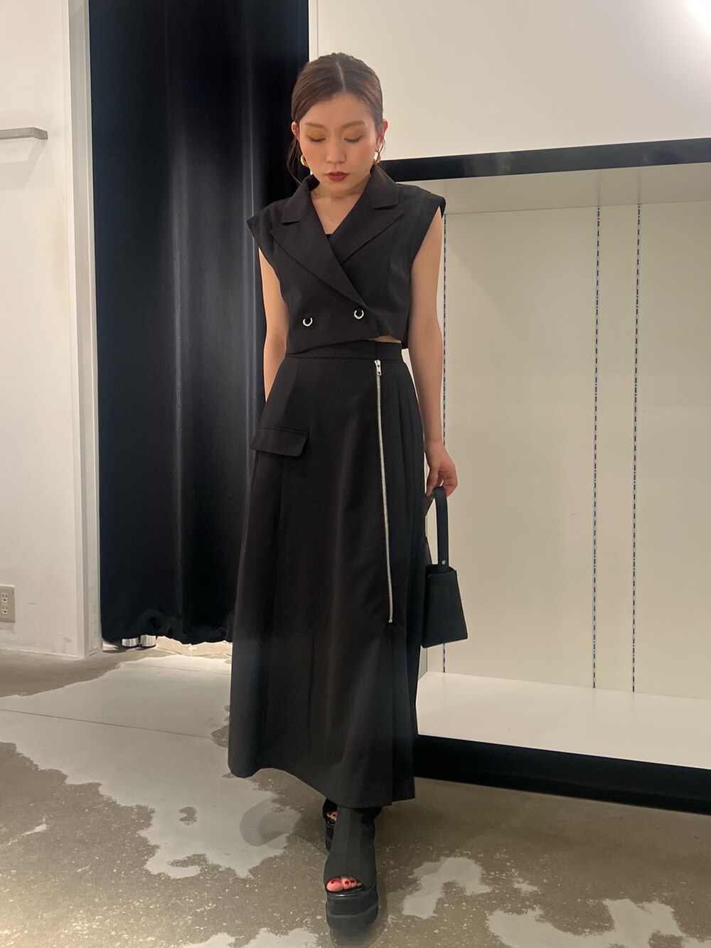 ブラック系のワンピース、ブラック系のサンダル、ブラック系のハンドバッグを着用したレディースの夏コーディネートの4枚目の写真