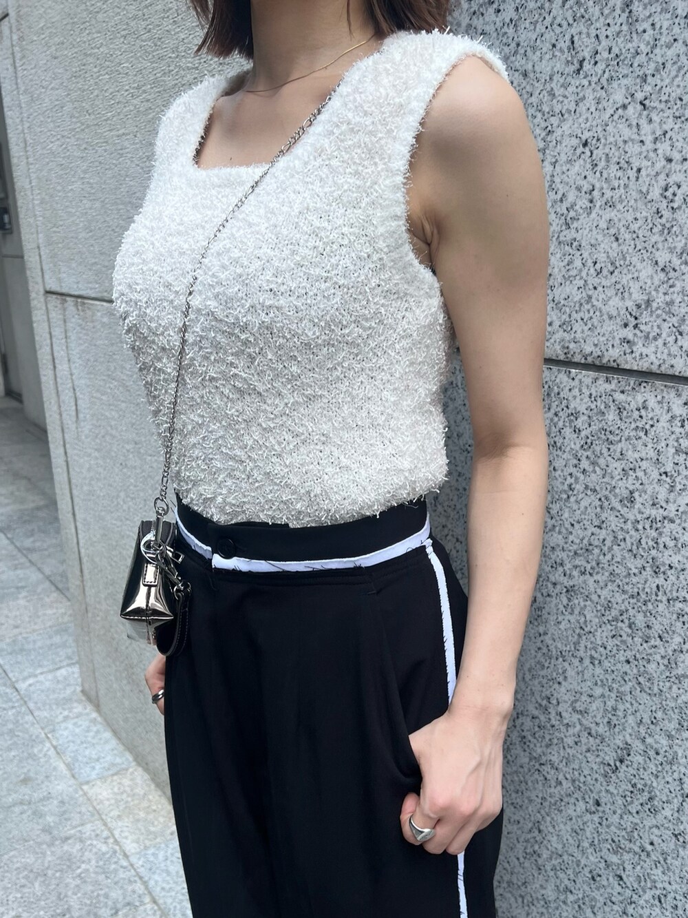 ホワイト系のニット/セーター、ブラック系のその他パンツ、ゴールド系のショルダーバッグを着用したレディースの夏コーディネートの7枚目の写真