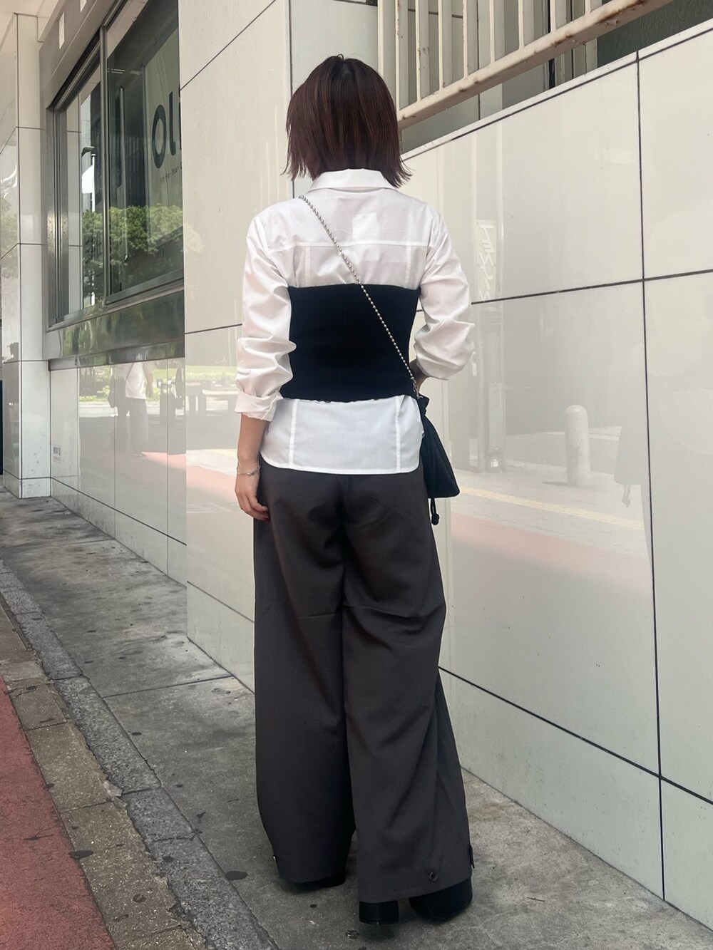 ブラック系のブーツ、ホワイト系のシャツ/ブラウス、ブラック系のニット/セーターを着用したレディースの秋コーディネートの2枚目の写真