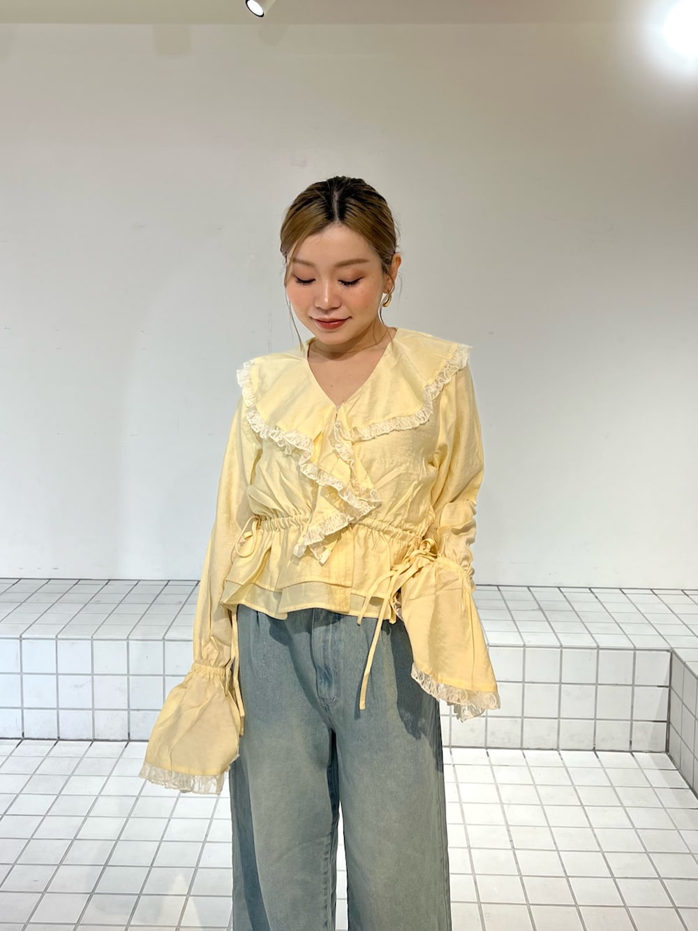 ブルー系のデニムパンツ、イエロー系のシャツ/ブラウス、ブラック系のサンダルを着用したレディースの春コーディネートの4枚目の写真