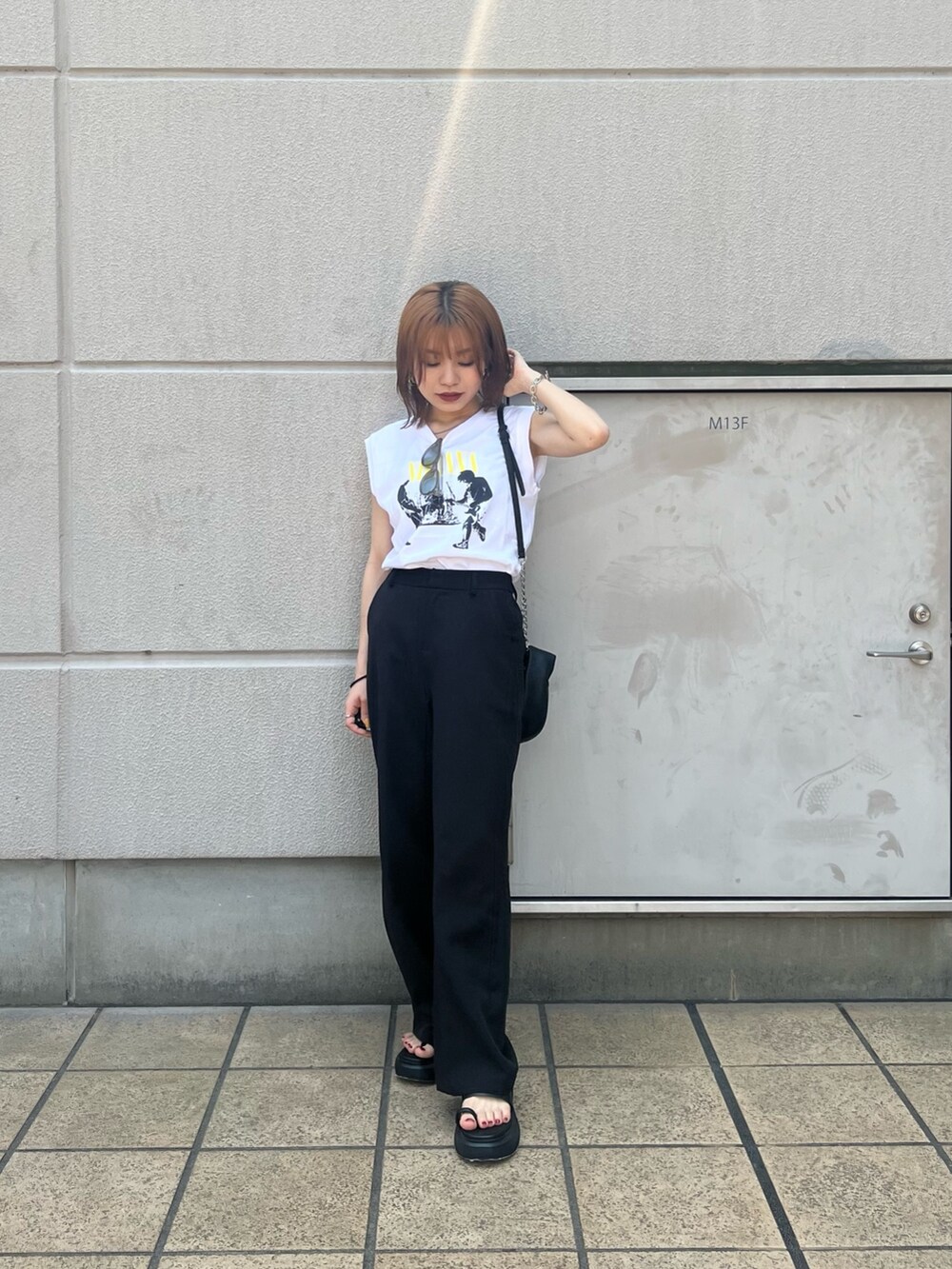 ホワイト系のタンクトップ、ブラック系のハンドバッグ、ブラック系のサンダルを着用したレディースの春コーディネートの4枚目の写真