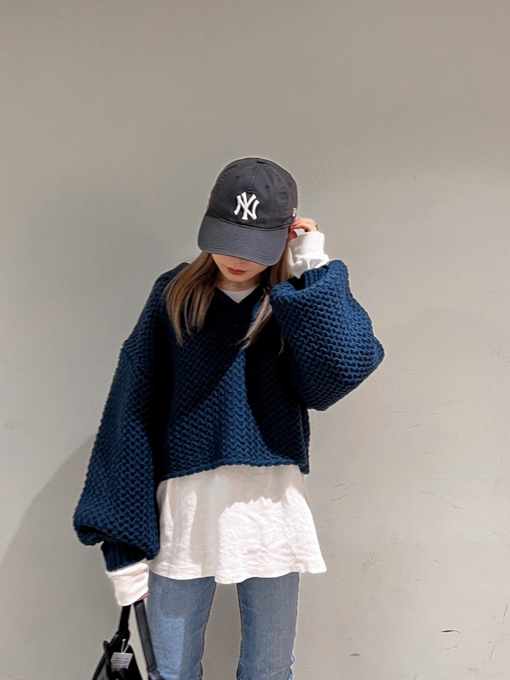 ブラック系のブーツ、ブルー系のニット/セーター、ブラック系のハンドバッグを着用したレディースの冬コーディネートの5枚目の写真