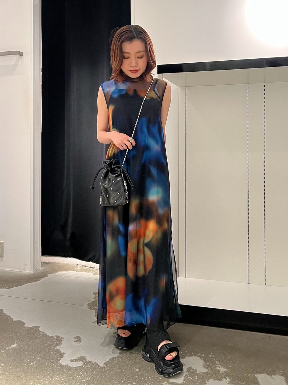 ブラック系のワンピース、ブラック系のサンダル、ブラック系のショルダーバッグを着用したレディースの春コーディネートの3枚目の写真