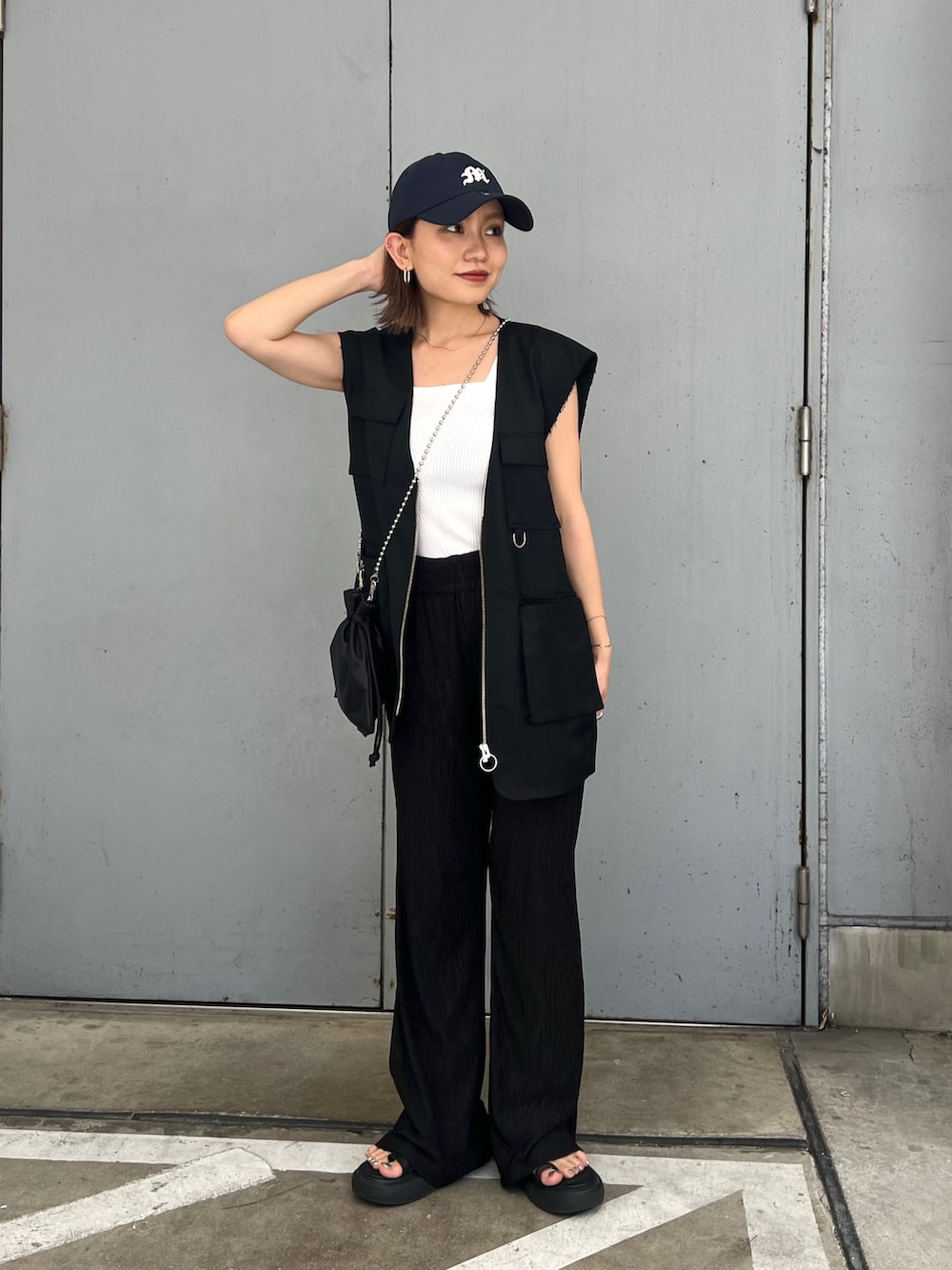ブラック系のベスト、ホワイト系のニット/セーター、ブルー系のキャップを着用したレディースの夏コーディネートの4枚目の写真