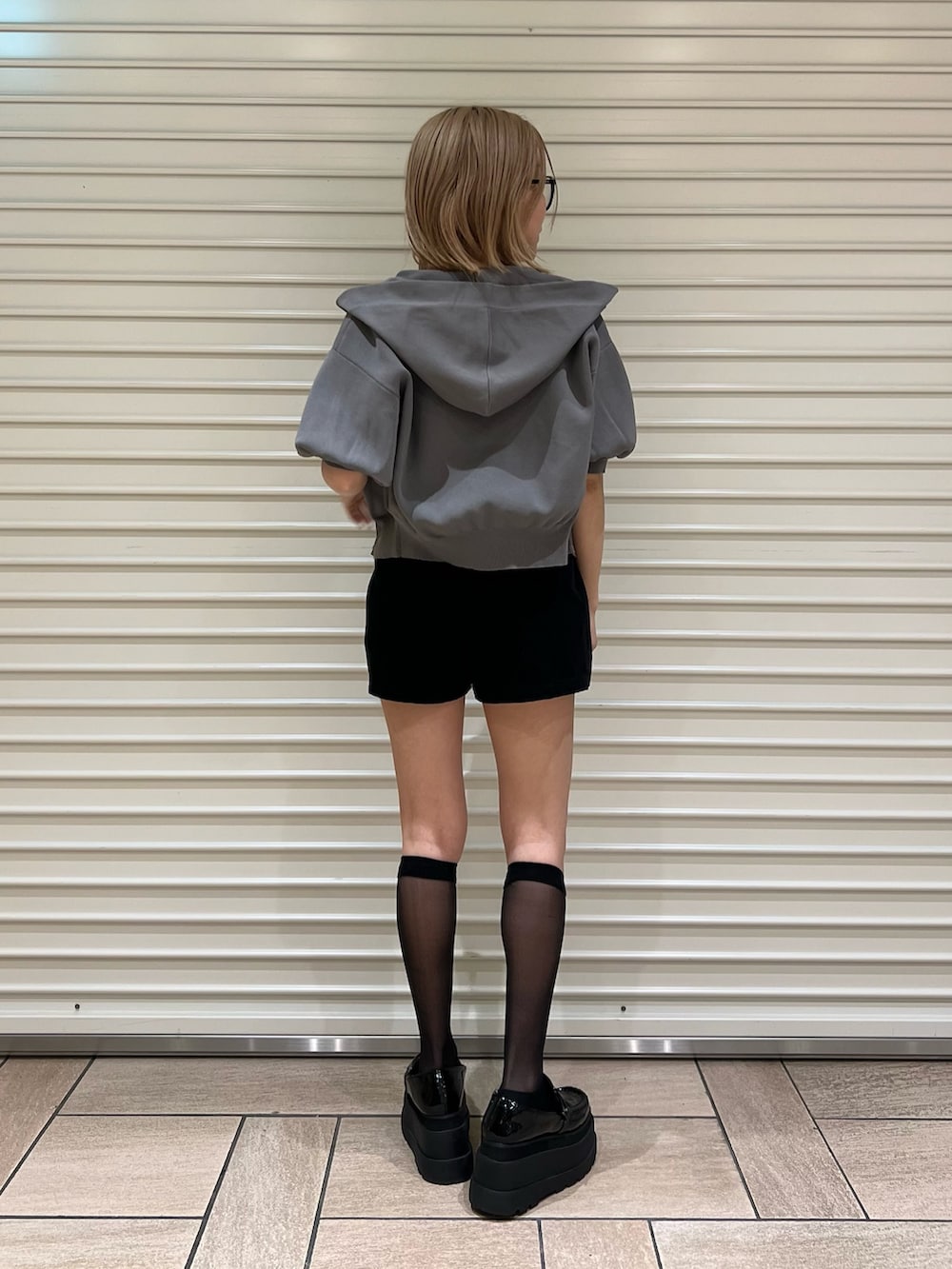 グレー系のパーカー、ブラック系のスカートを着用したレディースの夏コーディネートの3枚目の写真
