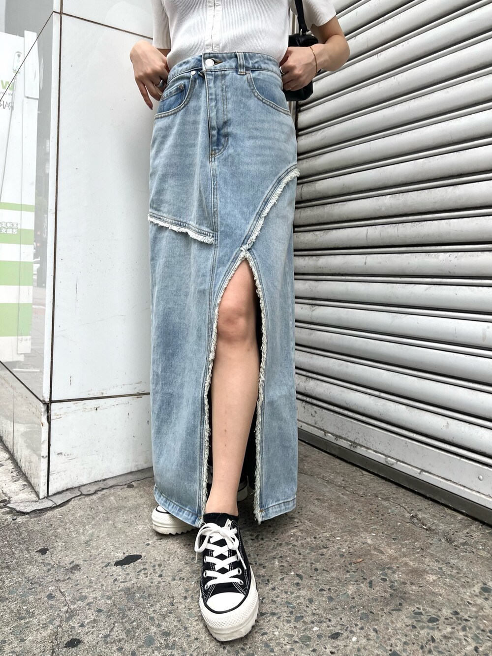 ホワイト系のニット/セーター、ブルー系のデニムスカート、ブラック系のハンドバッグを着用したレディースの夏コーディネートの8枚目の写真