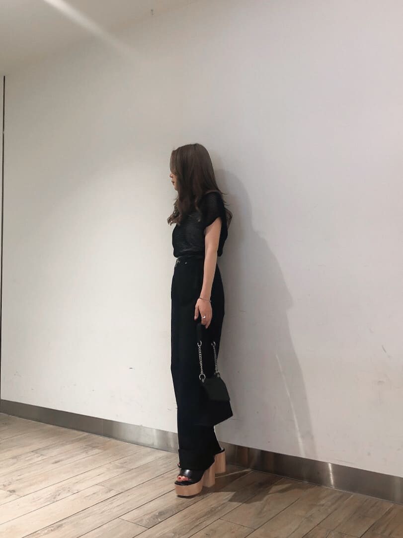 ブラック系のサンダル、ブラック系のハンドバッグ、ブラック系のデニムパンツを着用したレディースの春コーディネートの3枚目の写真