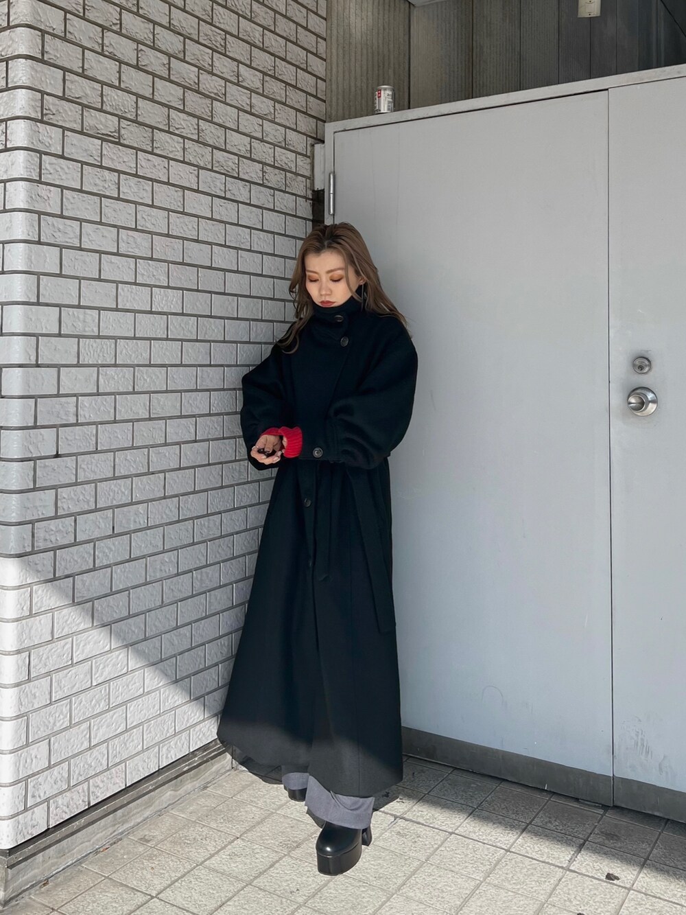 レッド系のニット/セーター、ブラック系のダウンジャケット/コート、ブラック系のブーツを着用したレディースの秋コーディネートの2枚目の写真