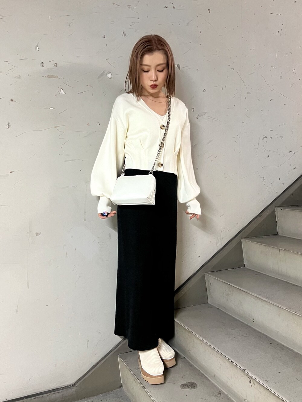 ホワイト系のブーツ、ブラック系のスカート、ホワイト系のカーディガン/ボレロを着用したレディースの冬コーディネートの2枚目の写真