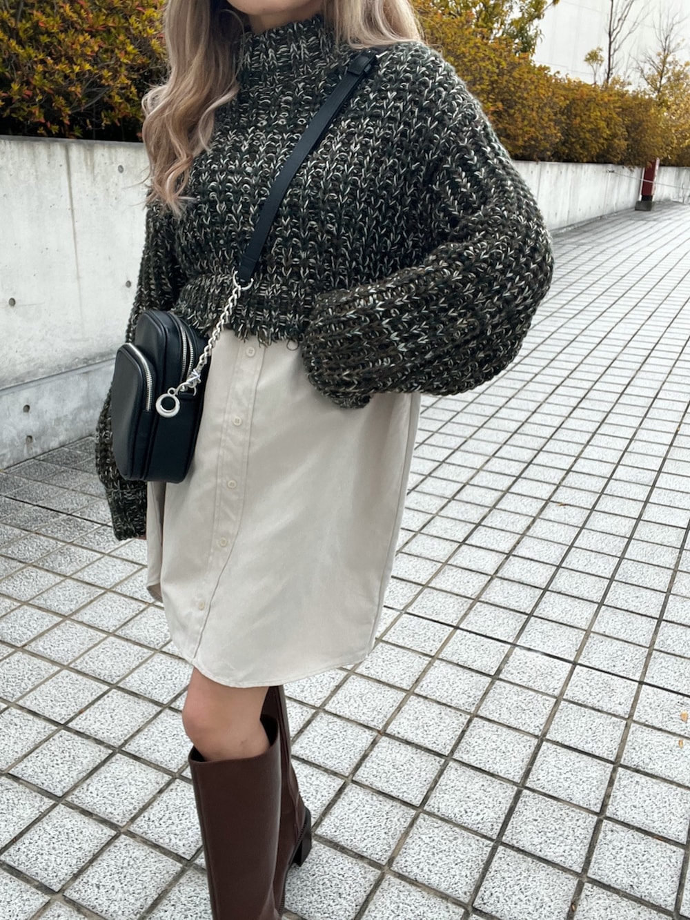 グリーン系のワンピース、ブラック系のショルダーバッグ、ブラウン系のブーツを着用したレディースの冬コーディネートの7枚目の写真