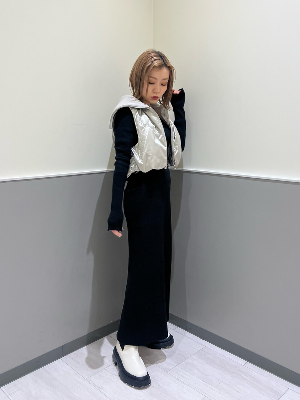 ホワイト系のブーツ、ブラック系のスカート、シルバー系のブルゾンを着用したレディースの冬コーディネートの2枚目の写真