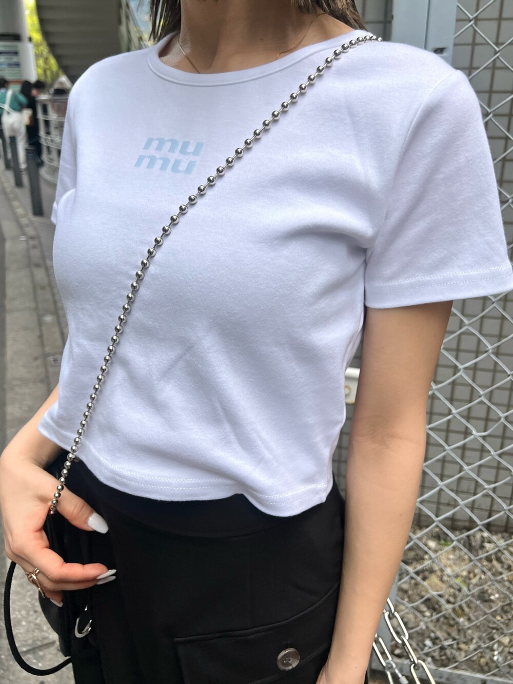 ホワイト系のTシャツ/カットソー、ブラック系のスカート、ブラック系のショルダーバッグを着用したレディースの春コーディネートの6枚目の写真