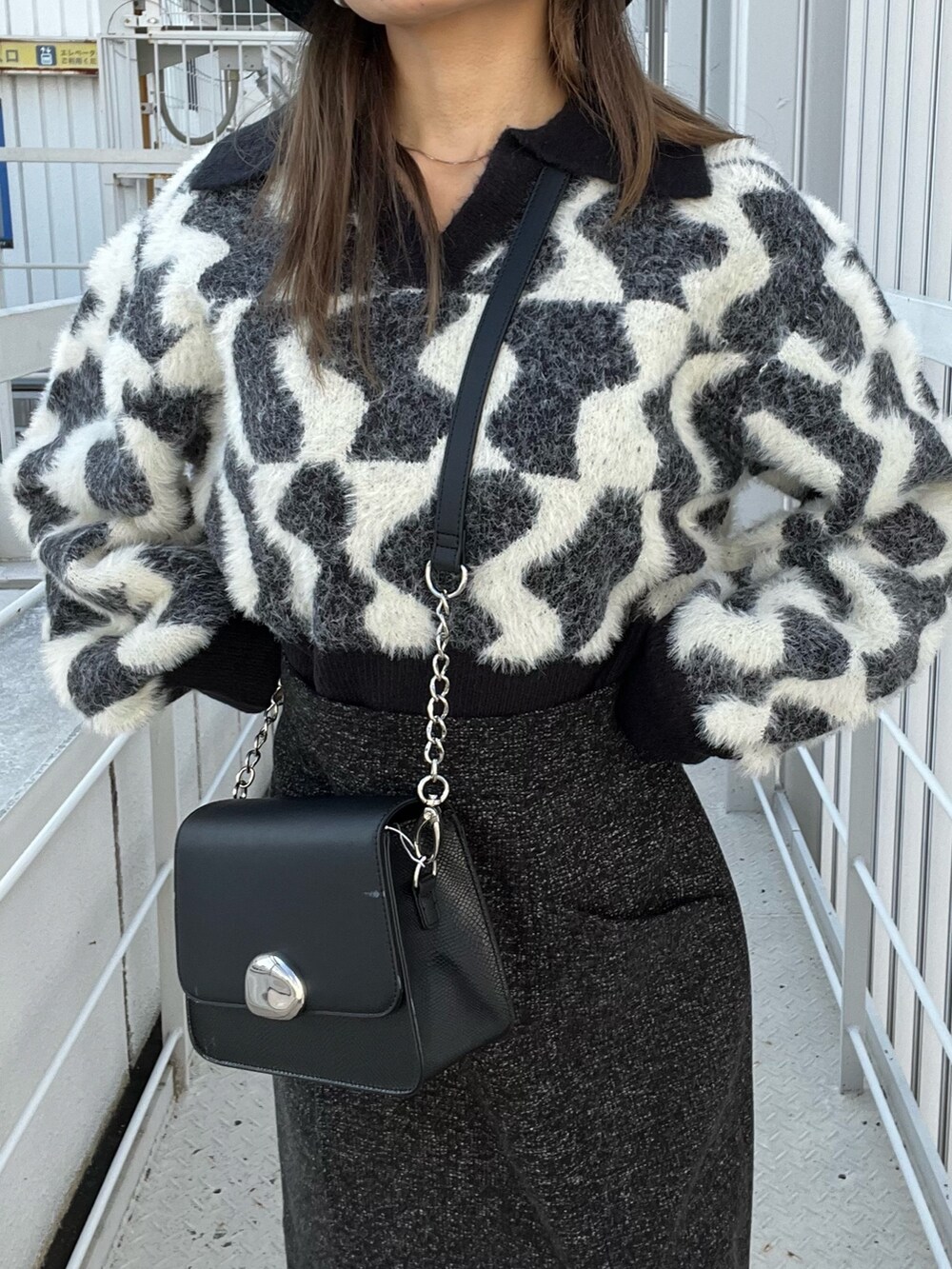 ブラック系のニット/セーター、ブラック系のスカート、ブラック系のショルダーバッグを着用したレディースの秋コーディネートの6枚目の写真