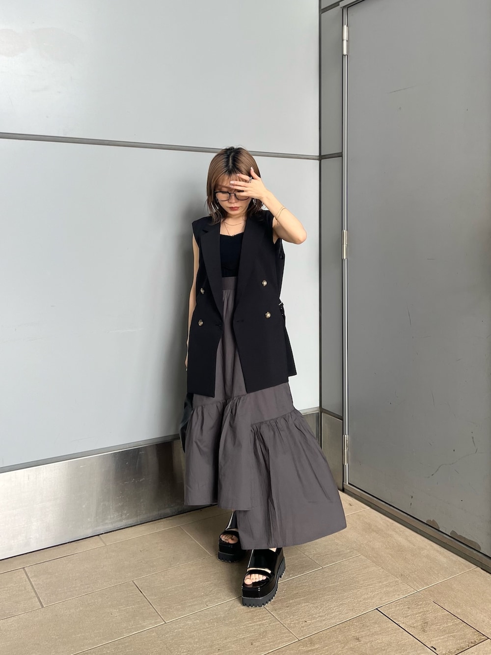 ブラック系のベスト、ブラック系のニット/セーター、グレー系のスカートを着用したレディースの夏コーディネートの3枚目の写真
