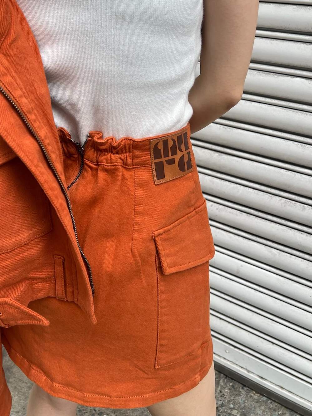 ホワイト系のニット/セーター、オレンジ系のデニムジャケット、オレンジ系のスカートを着用したレディースの夏コーディネートの8枚目の写真