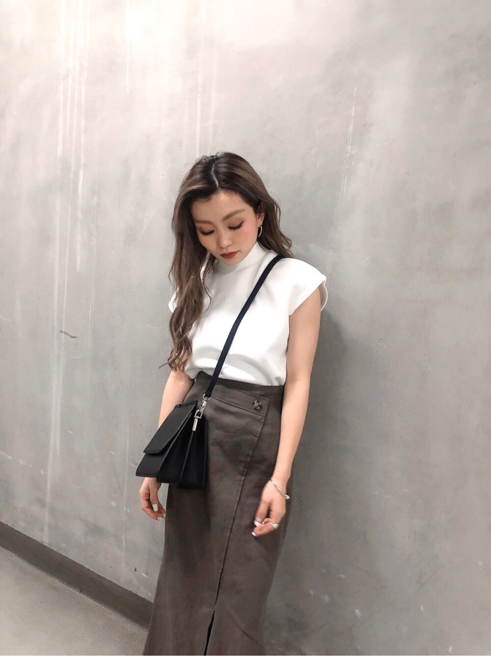 グレー系のスカート、ブラック系のハンドバッグ、ホワイト系のTシャツ/カットソーを着用したレディースの春コーディネートの3枚目の写真
