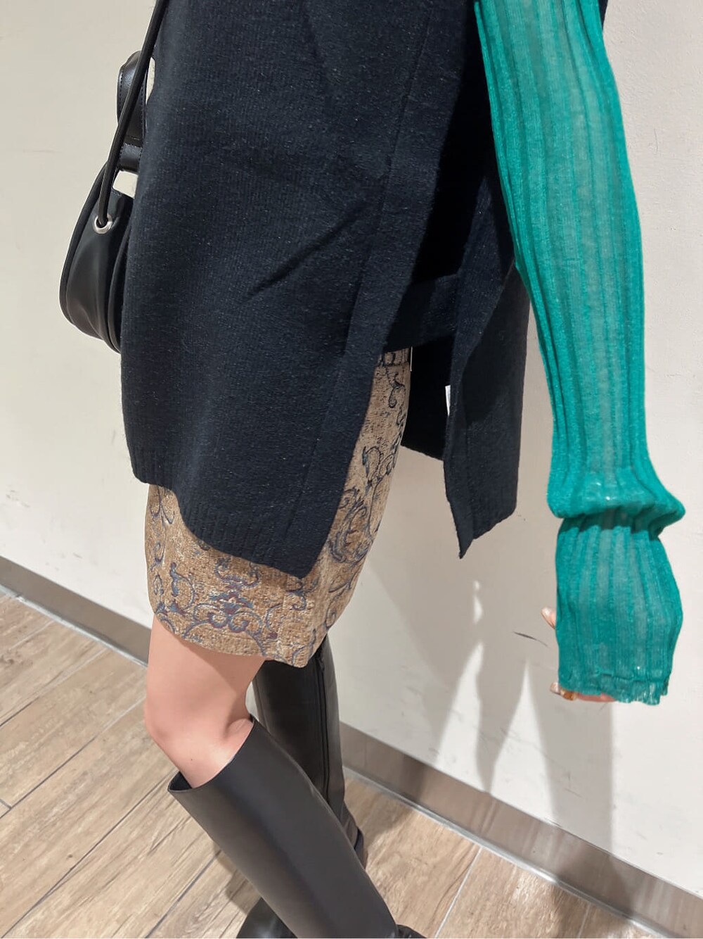 ブラック系のブーツ、グリーン系のニット/セーター、ブラウン系のスカートを着用したレディースの秋コーディネートの7枚目の写真