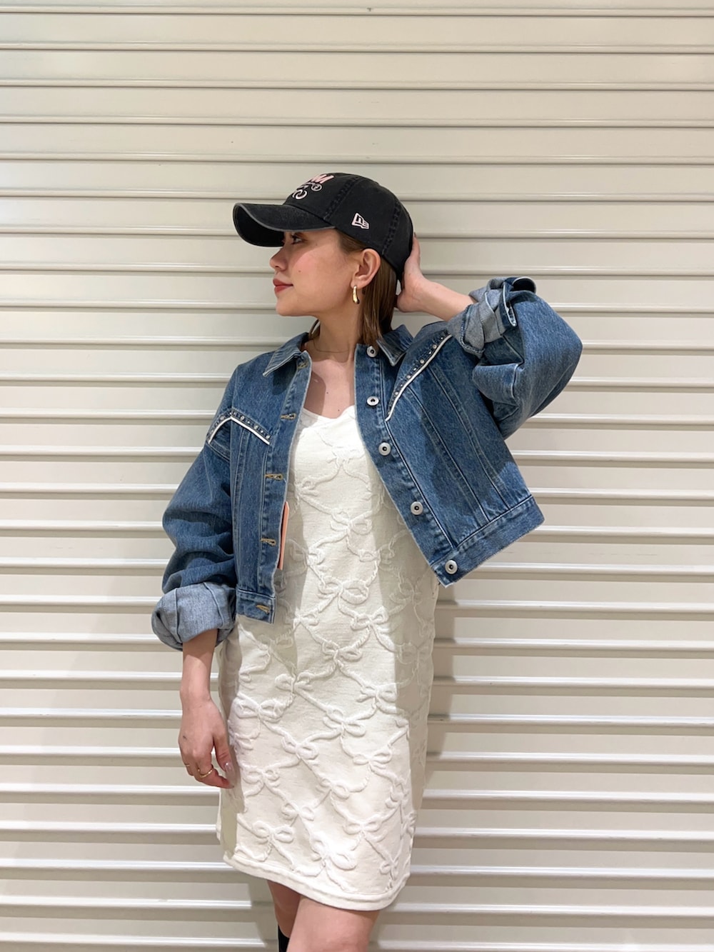 ブルー系のデニムジャケット、ホワイト系のワンピース、ブラック系のキャップを着用したレディースの春コーディネートの4枚目の写真