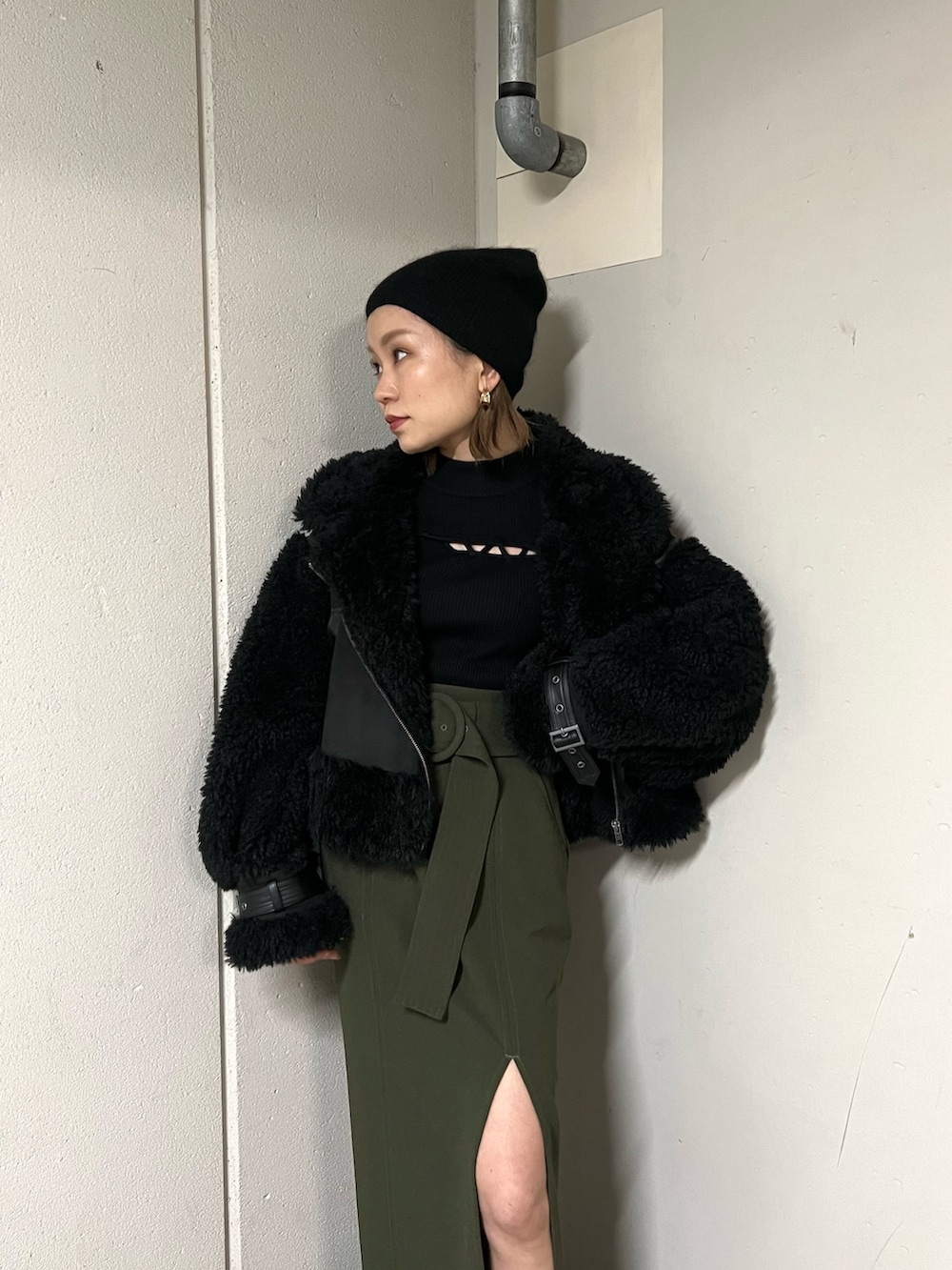 ブラック系のムートンコート、ブラック系のニット/セーター、グリーン系のスカートを着用したレディースの冬コーディネートの4枚目の写真