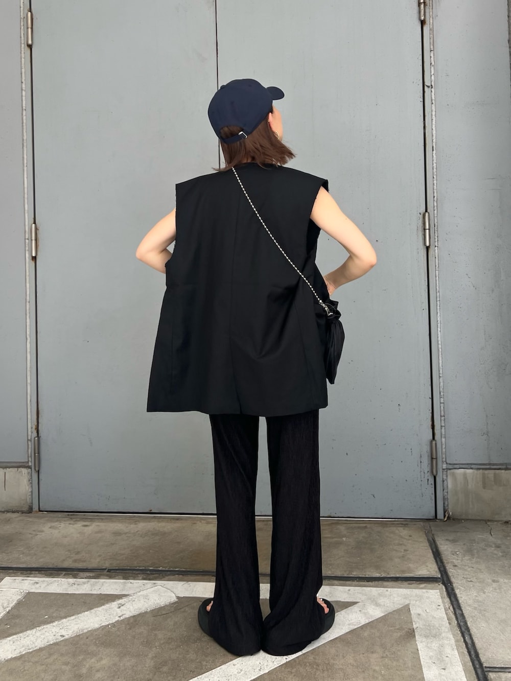 ブラック系のベスト、ホワイト系のニット/セーター、ブルー系のキャップを着用したレディースの夏コーディネートの3枚目の写真