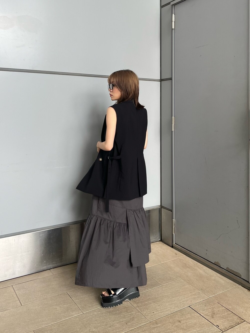 ブラック系のベスト、ブラック系のニット/セーター、グレー系のスカートを着用したレディースの夏コーディネートの2枚目の写真