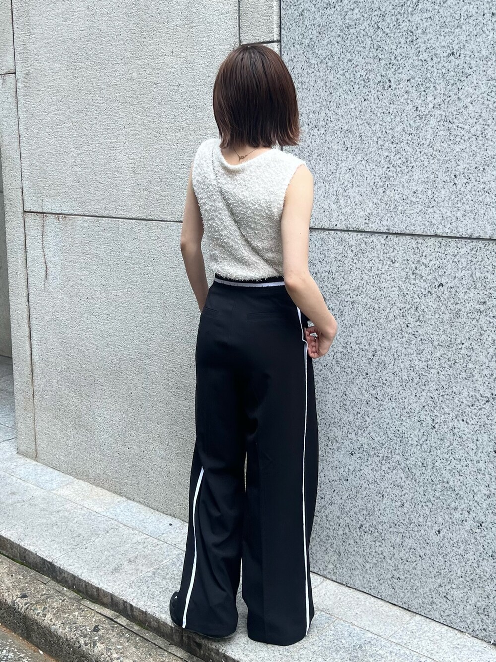 ホワイト系のニット/セーター、ブラック系のその他パンツ、ゴールド系のショルダーバッグを着用したレディースの夏コーディネートの3枚目の写真